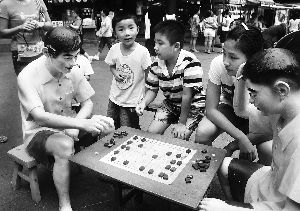 2011年8月,豫园老上海弄里风情夜市在豫园商城拉开帷幕,图为游客们在看雕塑下棋。 2011年8月,豫园老上海弄里风情夜市在豫园商城拉开帷幕,图为游客们在看雕塑下棋。