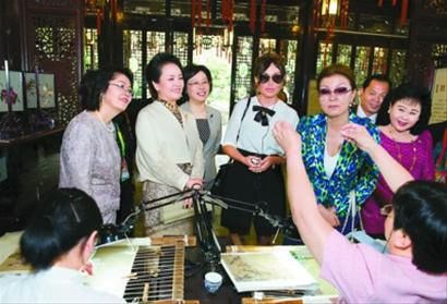彭丽媛和来宾欣赏顾绣传承人苏惠萍用细若游丝的线一次成功穿过针眼。 新华社发 彭丽媛和来宾欣赏顾绣传承人苏惠萍用细若游丝的线一次成功穿过针眼。 新华社发