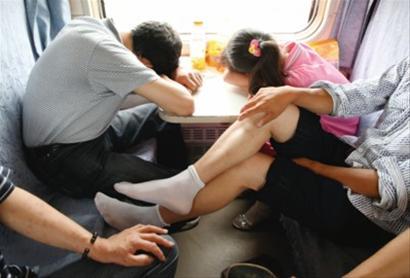 绿皮车车厢狭小,座位靠桌的乘客挤在桌板上睡午觉,旁边的乘客只能把脚