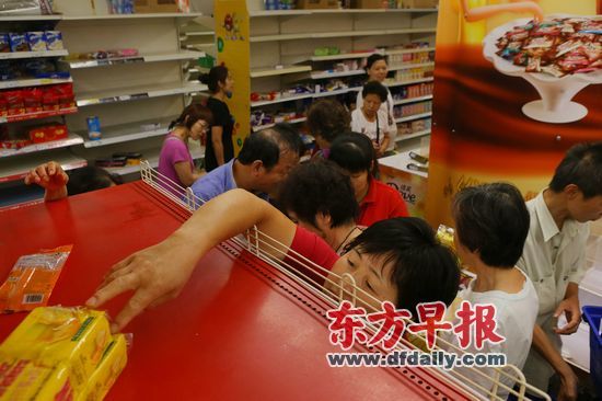 昨日,乐购长宁店,一名女士伸手拿货架上仅存的几包饼干。早报记者 王辰 图 昨日,乐购长宁店,一名女士伸手拿货架上仅存的几包饼干。早报记者 王辰 图