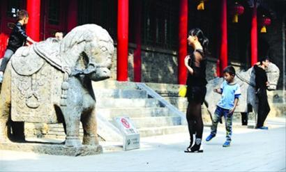 上海外滩,一名游客爬上雕塑。 晨报记者 杨眉 上海外滩,一名游客爬上雕塑。 晨报记者 杨眉