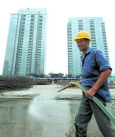 一名建筑工人在温州瓯江边的一处住宅前浇水,该楼盘的价格与高峰期相比已经“腰斩”。 一名建筑工人在温州瓯江边的一处住宅前浇水,该楼盘的价格与高峰期相比已经“腰斩”。